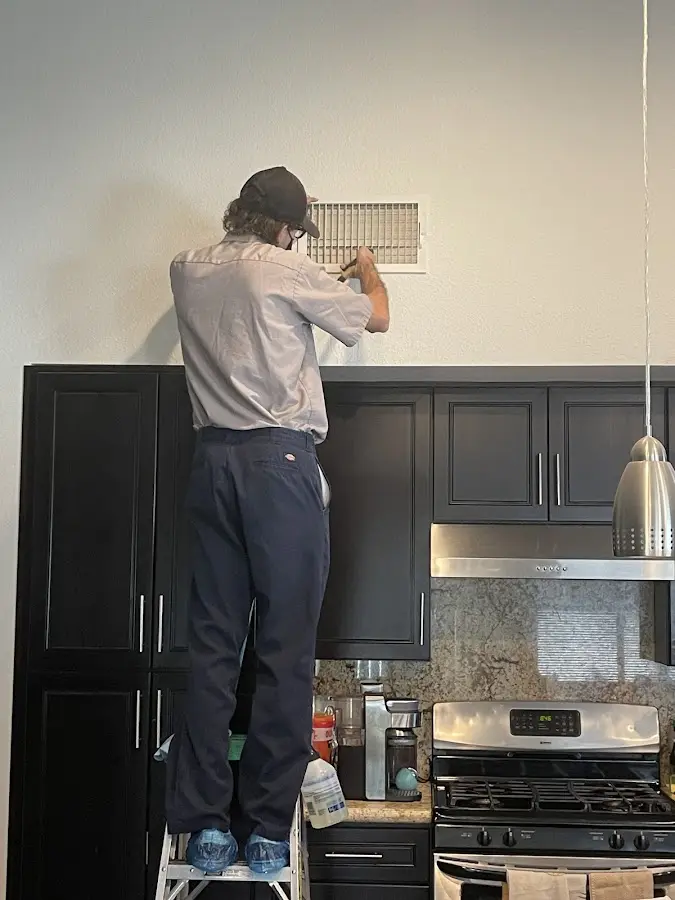 Technician inspecting an air vent during HVAC service in Grass Lake